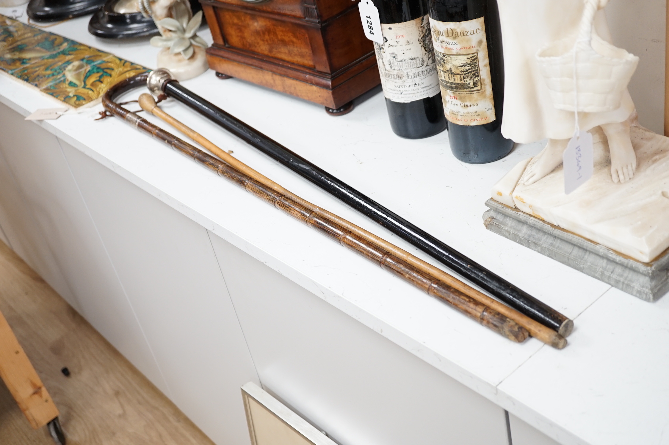 Three various walking canes including an inlaid tortoiseshell 'hidden compartment' cane, (two silver mounted), 90cm in length